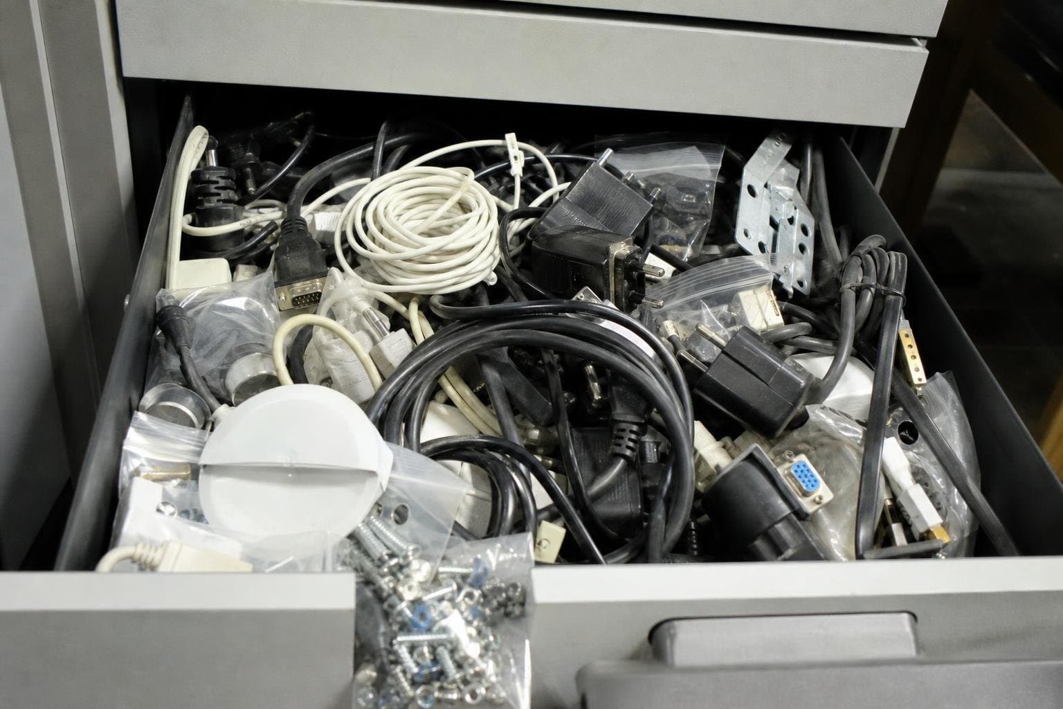A cluttered drawer stuffed with tangled cables and loose parts.