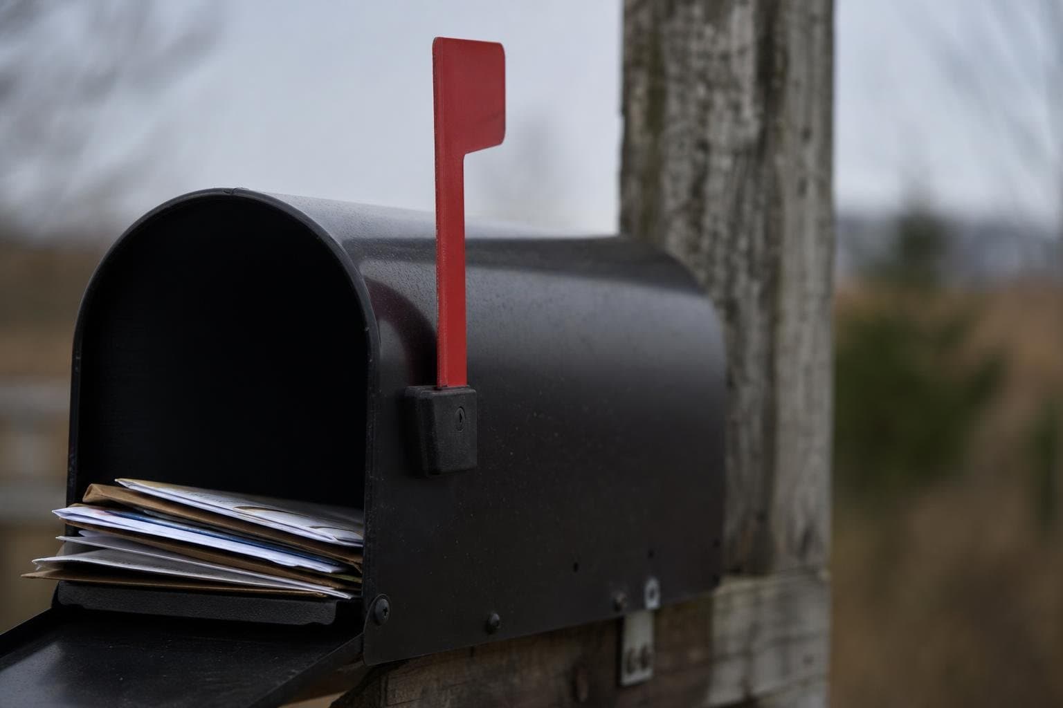 A mailbox with its red flag raised, signaling mail is waiting to be picked up.